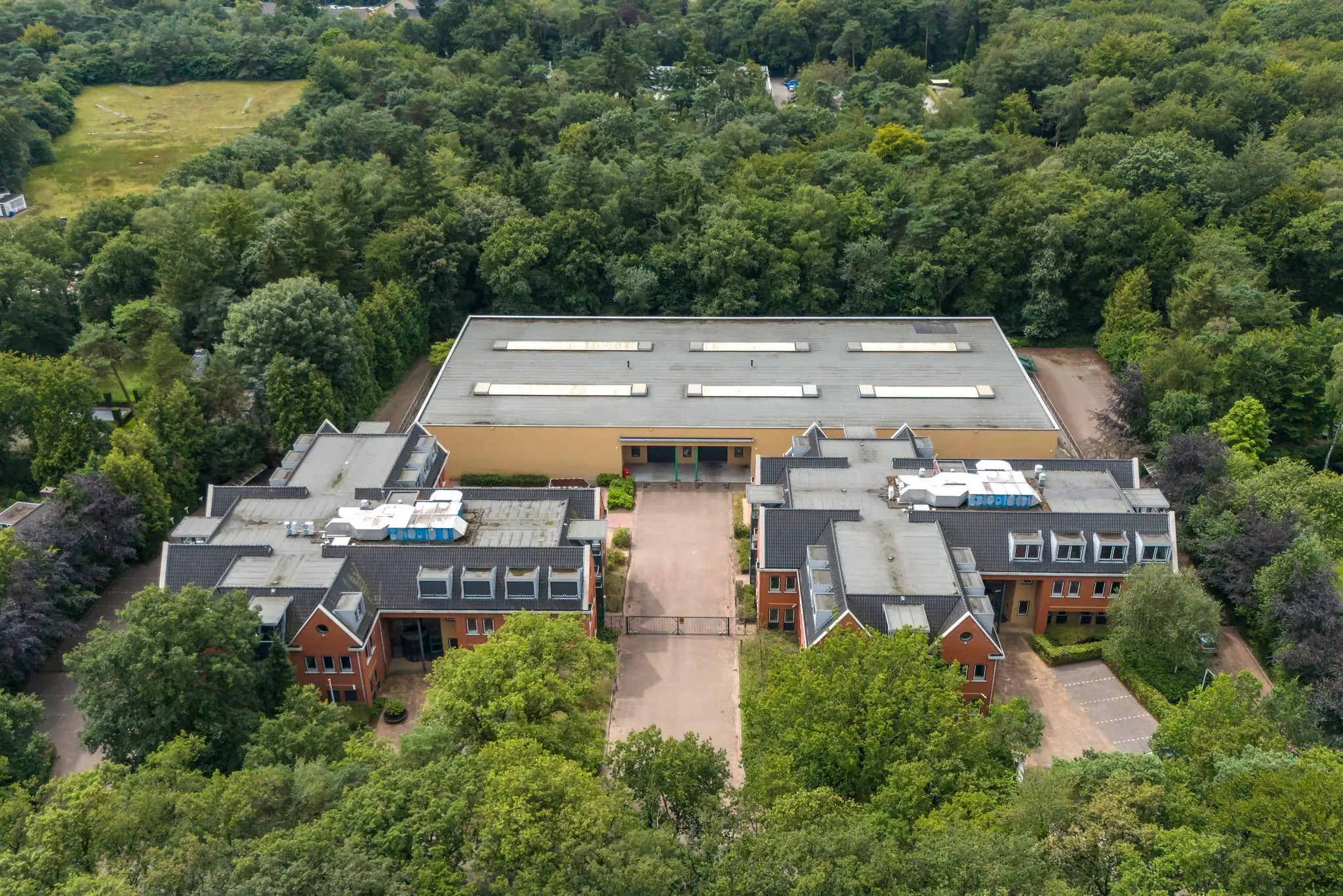 Luchtfoto van een groot gebouw aan de Laan Blussé van Oud-Alblas, omringd door dicht groen bosgebied.